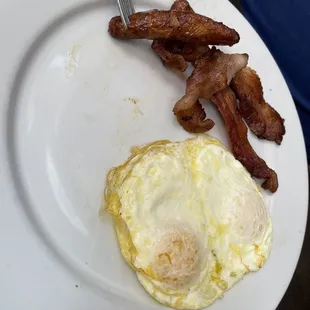 an egg and bacon on a plate