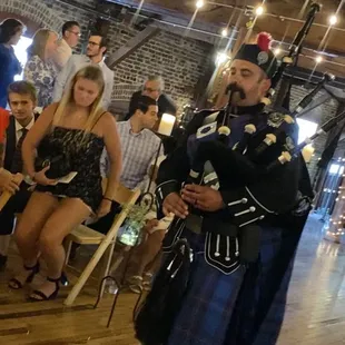 Brides brother piping his little sister down the aisle