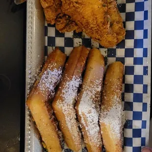 a plate of fried chicken, waffles, and lemon wedges