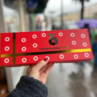 a person holding a box of donuts