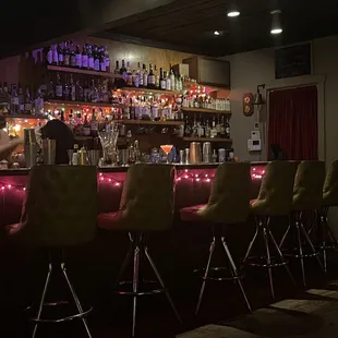 a row of bar stools in a dimly lit bar