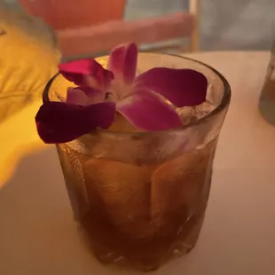a drink with a purple flower in a glass