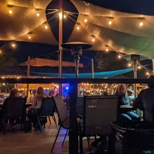 a group of people sitting at tables under umbrellas