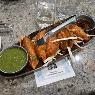 Tandoori momas (dumplings). The green sauce is cilantro and is delicious. The other sauce was a peppery oily sauce.