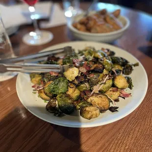 a plate of brussel sprouts and a glass of red wine