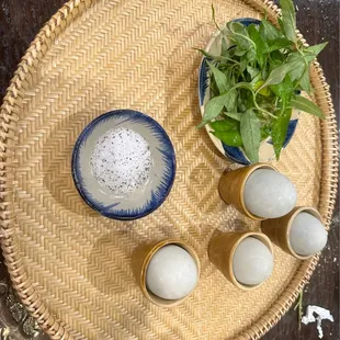 a bowl of milk, two eggs, and a plant on a wicker tray