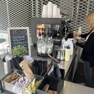 a woman standing at the counter of a coffee shop
