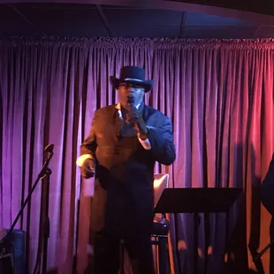 a man in a suit and hat playing a saxophone
