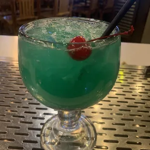 a green drink with a cherry in it