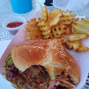 Pulled pork sandwich with pickles and coleslaw plus waffle fries.