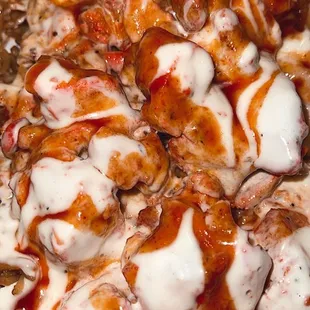 Chicken over rice platter with white &amp; bbq sauce.