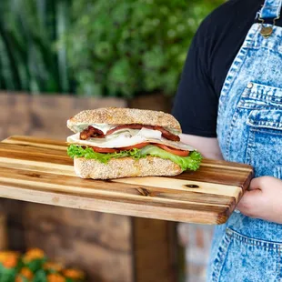 a person holding a sandwich on a cutting board