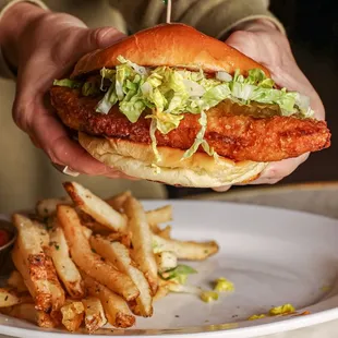 a person holding a sandwich and french fries