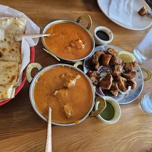 Chicken curry, lamb curry, butter naan bread, fish pakora with a sweet tamarind sauce and a cilantro sauce, and iced water.