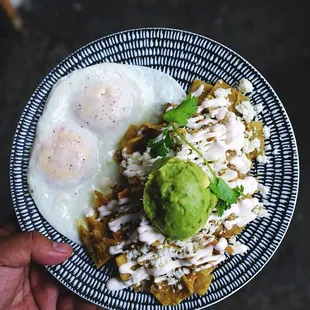 This is our chilaquiles plate with salsa verde, crema, queso fresco, avocado and eggs any style