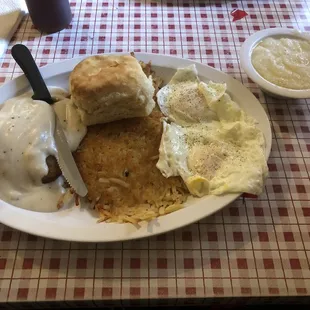 Country Fried Steak smothered in sausage gravy, with eggs over medium, hashbrowns, grits and a biscuit.