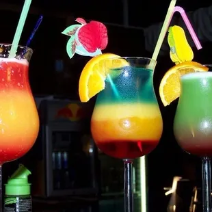 three colorful cocktails on a bar
