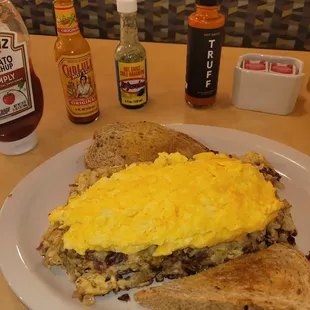 Corned beef hash with scrambled eggs and cheddar cheese, toast,  plus all the sauces to choose from.