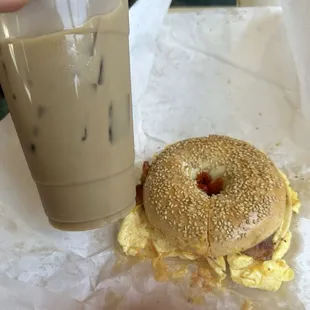 Bacon egg and cheese with salt pepper and ketchup on a sesame bagel and an iced coffee