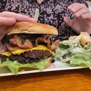 Bacon cheeseburger with mushrooms and caesar salad.