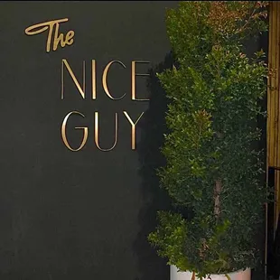 a man standing in front of the nice guy sign