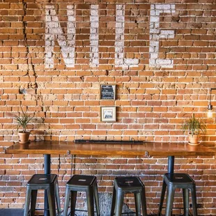 tables and stools in front of a brick wall