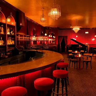 a dimly lit bar with red chairs