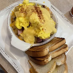 Breakfast hash with ham, bacon, potatoes, eggs and topped with hollandaise
