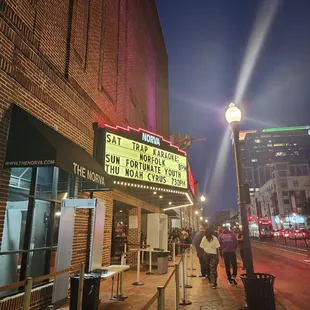 people walking down the sidewalk in front of a theater