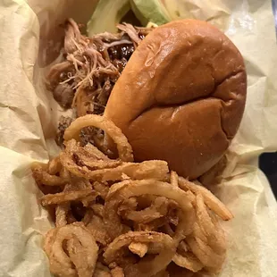 Pulled pork sandwich with onion rings.
