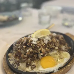 The Pork Sisig they brought again after we sent it back. Now it looks like Sisig and it&apos;s actually sizzling on the plate wow LOL