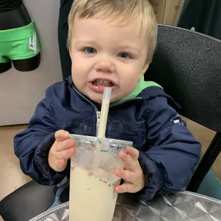 a toddler drinking milk from a plastic cup