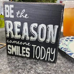 a sign that says be the reason someone smiles today