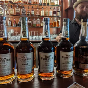 a man standing behind a row of bottles of whiskey