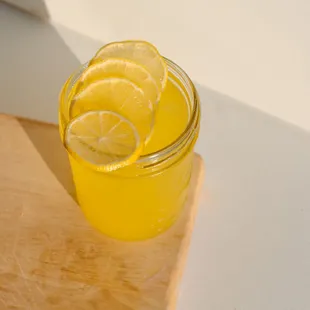 a glass of lemonade on a cutting board