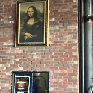 a painting of the mona painting on a brick wall