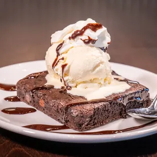 a piece of brownie topped with ice cream and caramel