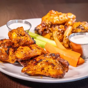 a plate of chicken wings, carrots, celery, and ranch dressing