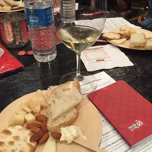 a plate of cheese, crackers, and a glass of wine