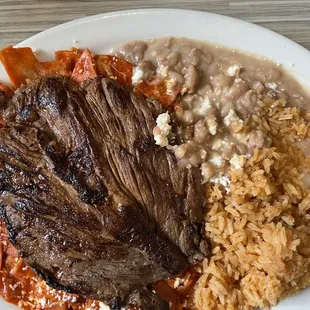 Ranchera steak on top of Chilaquiles in red sauce, refried beans, Spanish rice, queso fresco and black coffee!  Meat was delisted