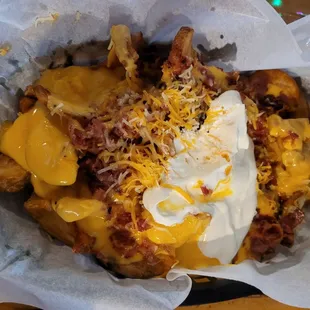 Rock Winders appetizer (wide wedge type of fry with nacho cheese, blended shredded cheese, onions, bacon &amp; sour cream) $10.50.