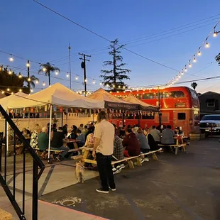 people sitting at picnic tables under string lights