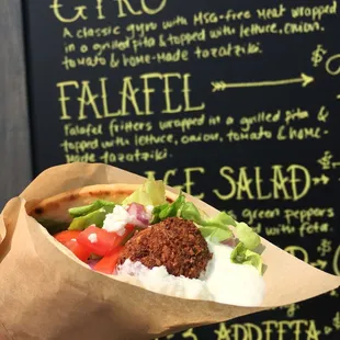 a hand holding a pita sandwich