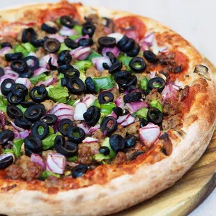 a pizza with olives, onions, and meat