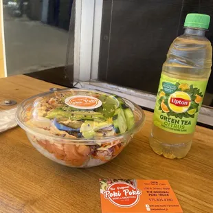 a bowl of salad and a bottle of soda
