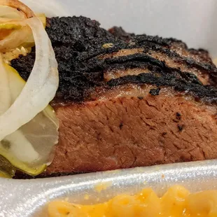 Close-up of chili-rubbed sliced beef brisket. A plate is $15.95 and comes with two sides, bread, hush puppies, onions, and pickles.