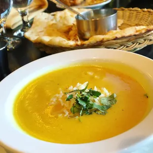 a bowl of soup with bread in the background