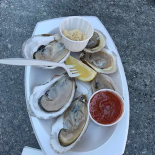 a plate of oysters with a side of ketchup