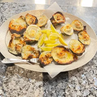 a plate of oysters with lemon wedges