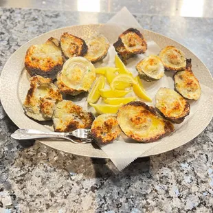 a plate of oysters with lemon wedges